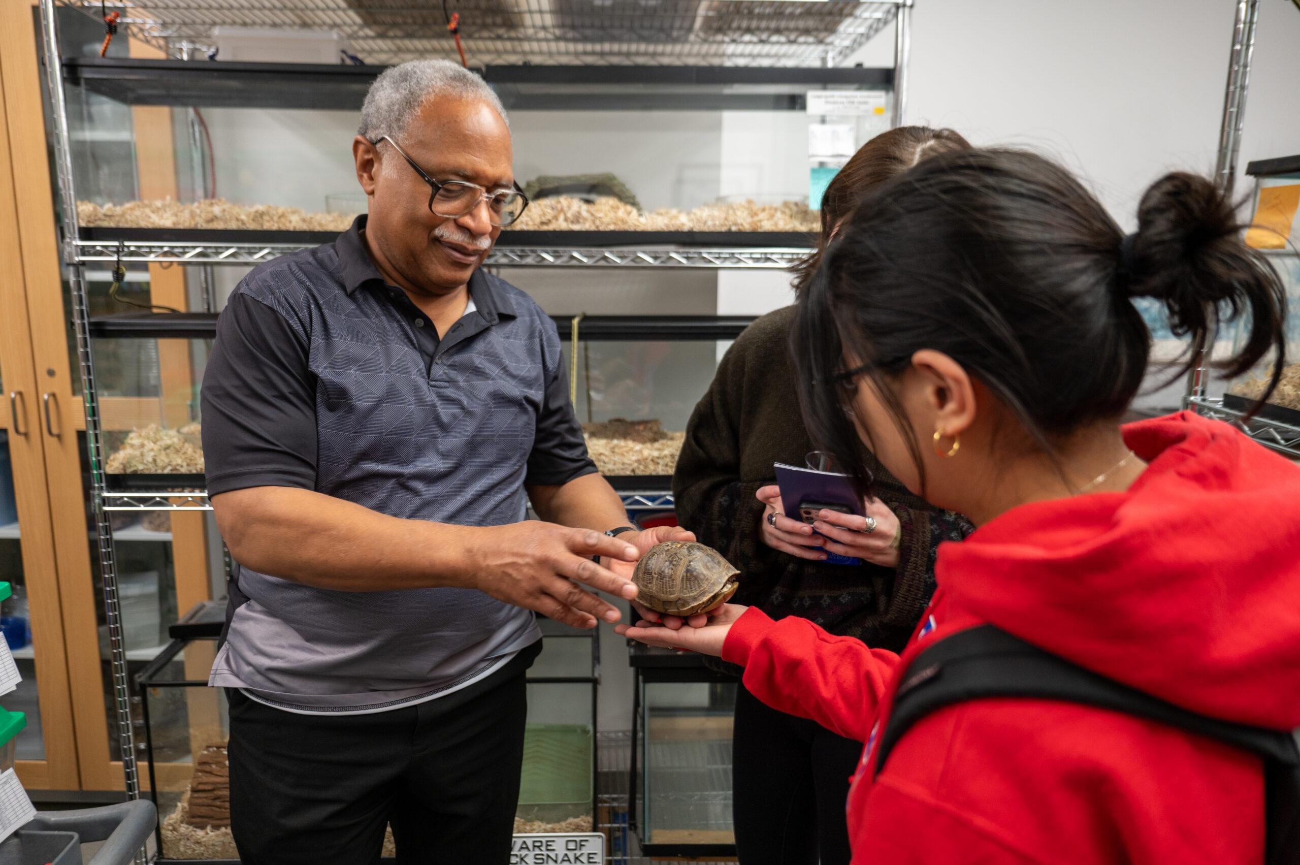 Professor and student petting a turtle